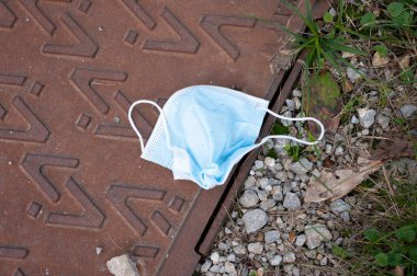 Çimenlerin üzerine yüz maskesi düşmesi doğayı kurtarır. çöp.