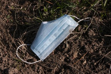 Çimenlerin üzerine yüz maskesi düşmesi doğayı kurtarır. Çöp. Koronavirüs zamanında