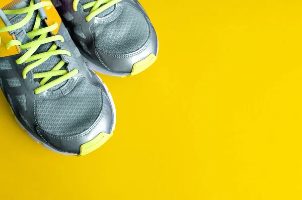 Sarı arka planda gri spor ayakkabılar, spor giysiler, evde spor kıyafeti, karantina zamanı eğitim. Renkler 2021 Boşluğu kopyala