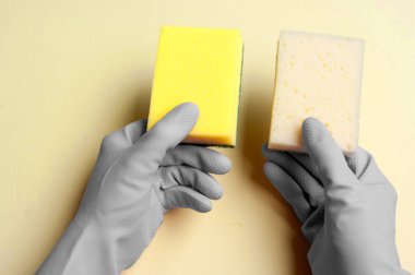 Gri lastik eldivenler temizlik için sarı süngerler tutuyor. Mutfak temizlik ekipmanları, bulaşık yıkama..