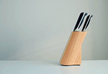 Beyaz bir zemin üzerinde ahşap bir stantta bıçak seti, boşluğu kopyala