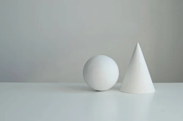 The geometric shapes of the ball  and  cone on white background, copy space.