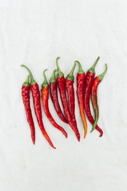 Red hot chili pepper on white cloth background, top view, copy space