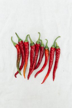 Red hot chili pepper on white cloth background, top view, copy space