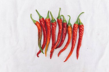 Red hot chili pepper on white cloth background, top view, copy space