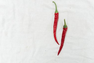Red hot chili pepper on white cloth background, top view, copy space