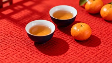 Çin çay seremonisi çaydanlık, fincanlar ve portakallar kırmızı arka planda.