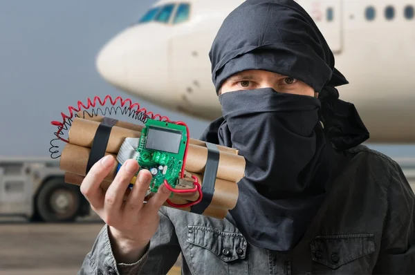 Concepto de terrorismo. Terrorista en aeropuerto tiene bomba de dinamita en la mano — Foto de Stock