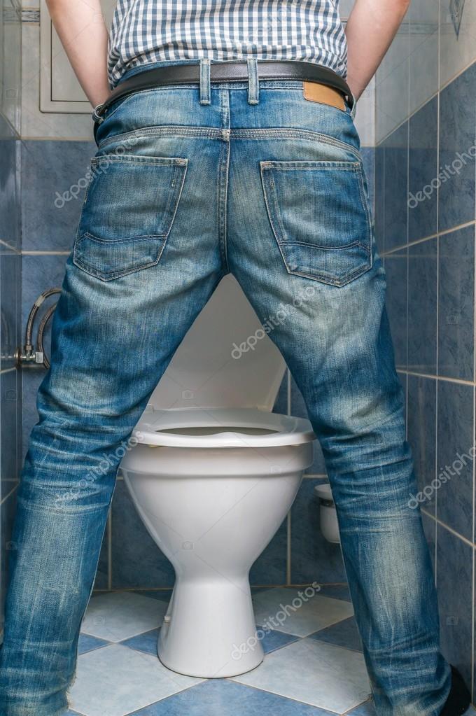A woman wearing white jeans is pissing in the public toilet