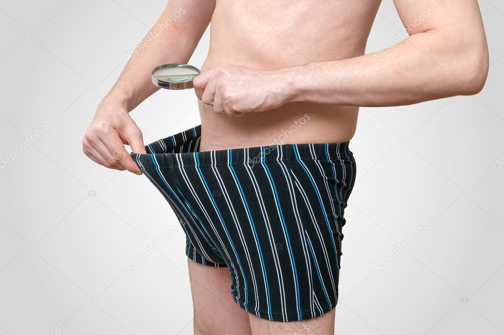 Impotence concept. Man is looking on his penis inside underwear with  magnifying glass. Stock Photo by ©vchalup2 102154974