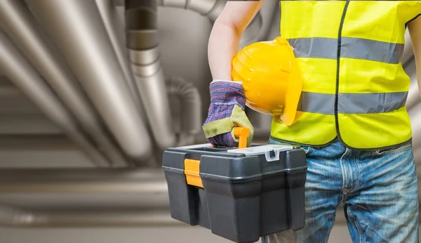 Concepto industrial. Trabajador con herramientas y tuberías en segundo plano —  Fotos de Stock