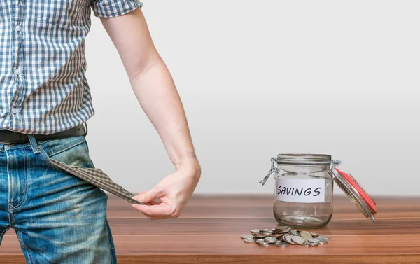 Man showing pocket as no money symbol and jar with coins. — Stock Photo, Image