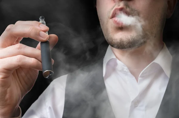 Ο άνθρωπος vaping ηλεκτρονικό τσιγάρο και φυσώντας καπνό. — Φωτογραφία Αρχείου