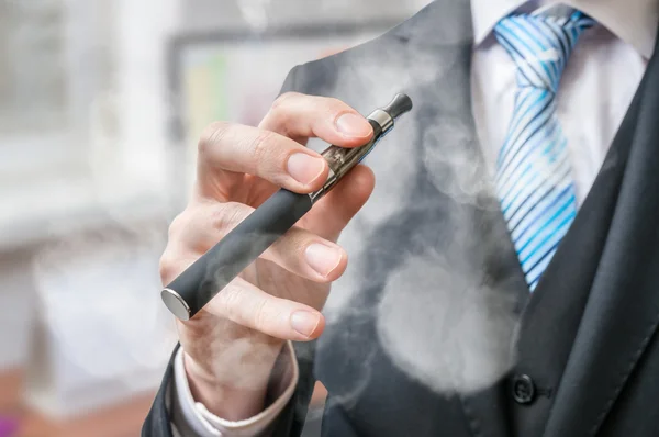 Empresário detém vaporizador e fuma cigarro eletrônico . — Fotografia de Stock