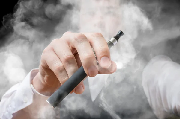 Κάπνισμα άνθρωπος κατέχει ηλεκτρονικό τσιγάρο στο χέρι. Πολύ καπνό. — Φωτογραφία Αρχείου