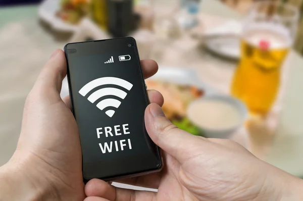 Homem detém smartphone e está usando Wi-Fi gratuito no restaurante . — Fotografia de Stock