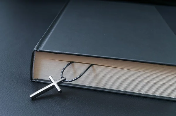 Conceito de teologia. Cruz metálica e Bíblia Sagrada no backgro preto — Fotografia de Stock