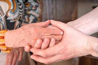 Adam eldery kadının ellerini tutar. Üst düzey yardım kavramı.