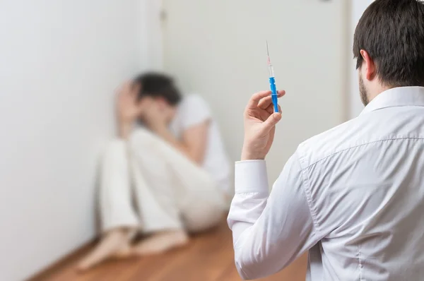 Psychiatrist doctor holds syringe. Crazy or insane patient in background. — Stock Photo, Image