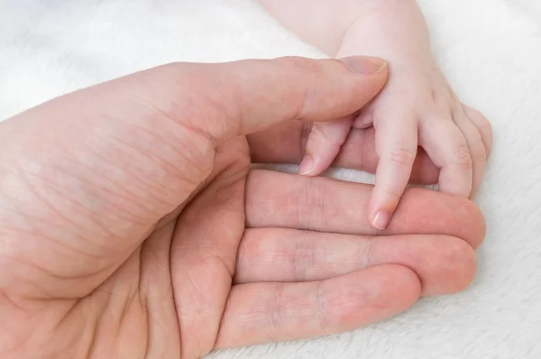 Conceito de cuidados infantis. Homem segura a mão de seu bebê . — Fotografia de Stock