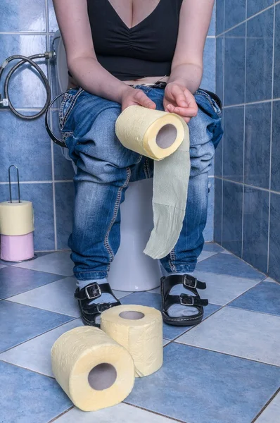 Woman suffers from diarrhea is sitting in restroom and holds toilet paper. — Stock Photo, Image