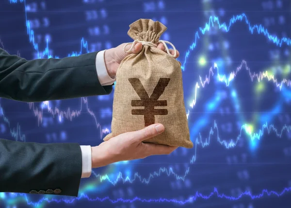 Mão de homem de negócios segura saco cheio de dinheiro com sinal de iene . — Fotografia de Stock