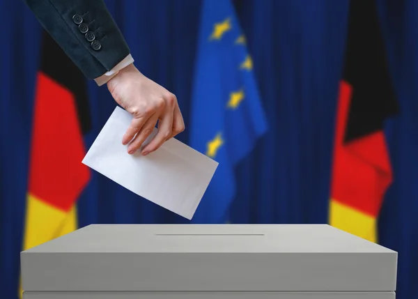 Elecciones en Alemania. Votante sostiene sobre en mano sobre papeleta de votación . — Foto de Stock