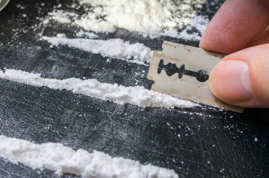 Adam burundan enfiye şeklinde çekmek için kokain beyaz toz satırlık yapıyor.