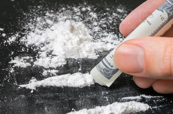 Junkie is snorting cocaine white powder with rolled banknote. Na