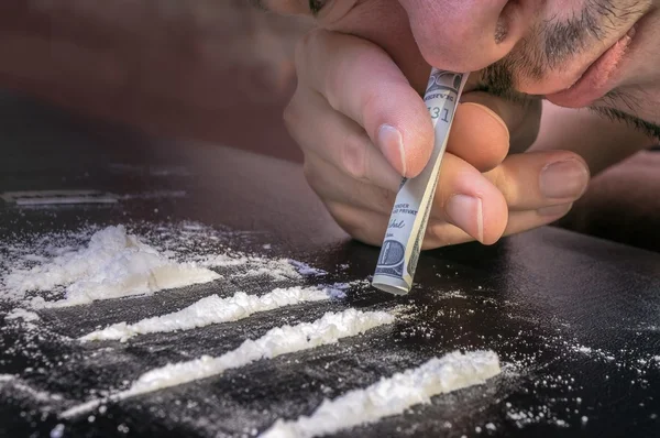 O drogado está a cheirar cocaína em pó com notas enroladas. Conceito de narcóticos . — Fotografia de Stock