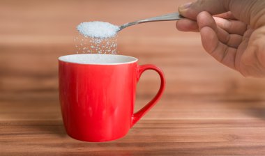 El kırmızı çay fincan şeker döküyor. Sağlıksız beslenme kavramı
