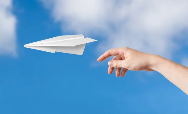 Mão está jogando origami avião de papel. Céu azul no fundo . — Fotografia de Stock