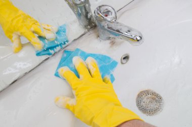 Ev kavramı. Kişi bez ile banyo lavabo temizliyor.