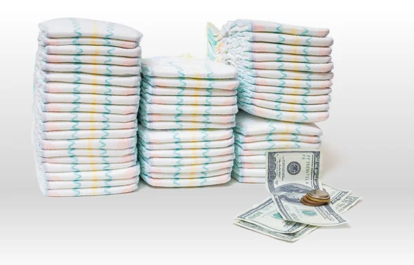 Cuidados infantis caros. Uma pilha de fraldas e dinheiro em fundo branco — Fotografia de Stock