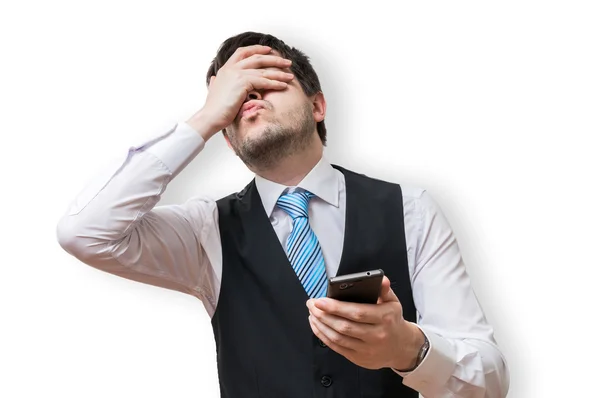 Disappointed man holds smartphone and covers his face with hand. Isolated on white background. — Stock Photo, Image