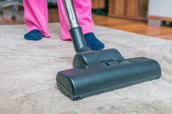 Woman is vacuuming carpet with vacuum cleaner. — Stock Photo, Image