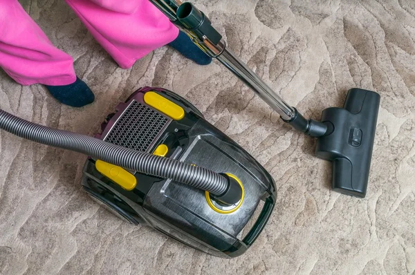 Woman is vacuuming carpet with vacuum cleaner. — Stock Photo, Image