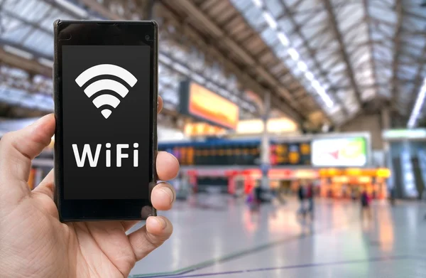 Homem detém smartphone com Wi-Fi gratuito na estação ferroviária . — Fotografia de Stock