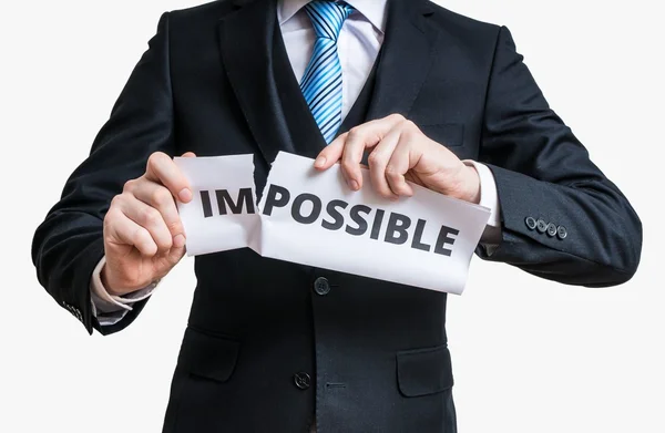 Концепция возможности. Человек рвет бумагу невозможным словом, чтобы сделать это возможным. Изолированный на белом фоне . — стоковое фото