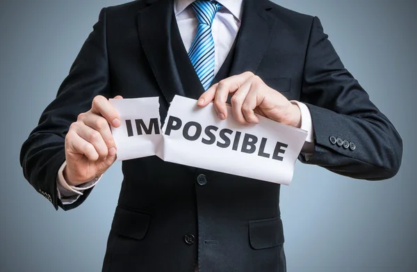 Conceito de possibilidade. Empresário está rasgando papel com palavra impossível para torná-lo possível . — Fotografia de Stock