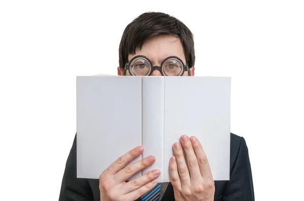 Young shy man is reading and is covering his face and is hiding behind book. Isolated on white background. — Stock Photo, Image