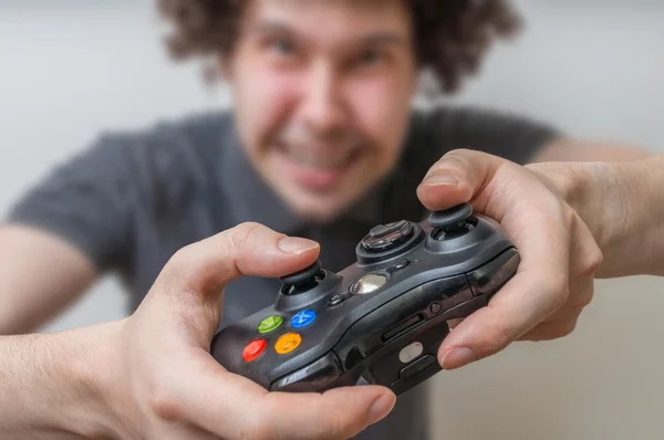 Jovem está jogando videogames e detém joystick ou controlador — Fotografia de Stock