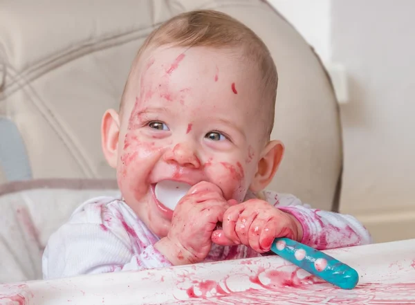 Bebé feliz está comendo e lambendo lanche da colher . — Fotografia de Stock
