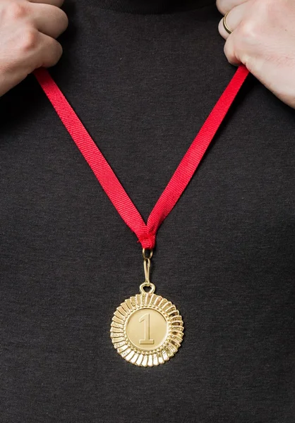 Homem está segurando e colocando em medalha de ouro no peito . — Fotografia de Stock