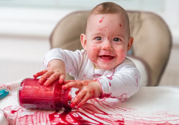 Bebê bagunçado e sujo está comendo lanche com as mãos . — Fotografia de Stock