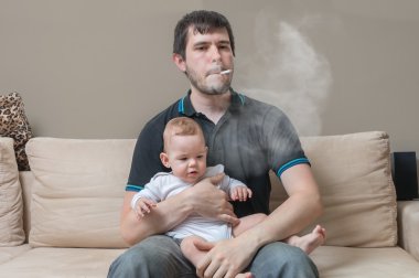 Bad parent - smoking father is holding baby in hands. clipart