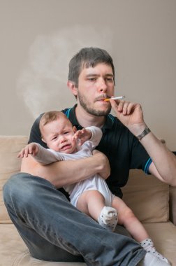 Bad father is smoking cigarette and holding baby. clipart