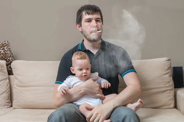 Złym rodzicem - palenie ojciec trzyma dziecko w ręce. — Zdjęcie stockowe