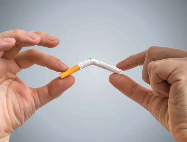 Deixar de fumar conceito. As mãos estão a partir o cigarro ao meio . — Fotografia de Stock