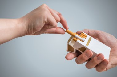 Hand is taking cigarette from cigarette pack an accepting an offer. clipart